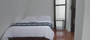 a bedroom with a bed with white sheets and a table at Tungurahua Eco Lodge INN BAÑOS in Quillullaco