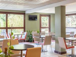 a waiting room with tables and chairs and windows at ibis Auch in Auch