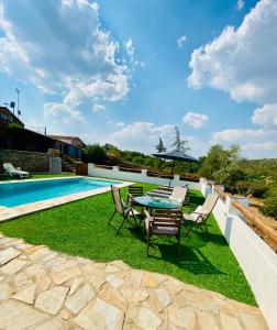 a patio with a table and chairs next to a swimming pool at Casa La Rocita in Badajoz