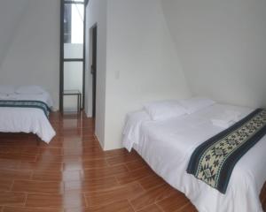 a bedroom with two beds and a wooden floor at Tungurahua Eco Lodge INN BAÑOS in Quillullaco +2 photos