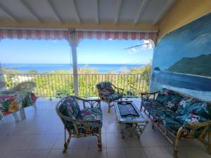 a porch with chairs and tables and a view of the ocean at KAZ A CE TI MOUN LA, à Deshaies in Deshaies