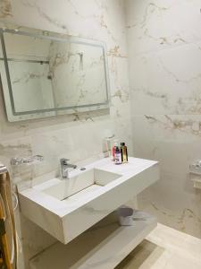 a white bathroom with a sink and a mirror at Appartement Kais in Laayoune