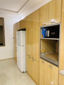 a kitchen with a white refrigerator and wooden cabinets at Appartement Kais in Laayoune