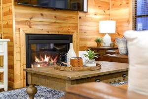a living room with a fireplace in a log cabin at Luxury Cabin Near Lake - Sauna, Cold Plunge, Hot Tub, Fire Pit, & Games in Broken Bow