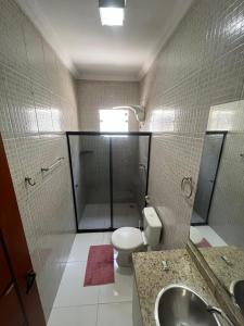 a bathroom with a toilet and a sink and a mirror at 2 quartos com garagem coberta in Vitória da Conquista