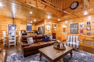 a living room with a leather couch and a table at Luxury Cabin Near Lake - Sauna, Cold Plunge, Hot Tub, Fire Pit, & Games in Broken Bow