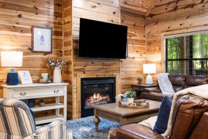 a living room with a fireplace and a flat screen tv at Luxury Cabin Near Lake - Sauna, Cold Plunge, Hot Tub, Fire Pit, & Games in Broken Bow