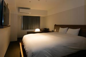 a bedroom with a large bed with a light on it at BRENZA HOTEL in Kobe
