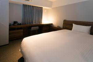 a hotel room with a white bed and a desk at BRENZA HOTEL in Kobe