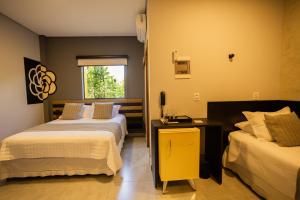 a hotel room with two beds and a window at Hotel Flores de Holambra in Holambra +138 photos