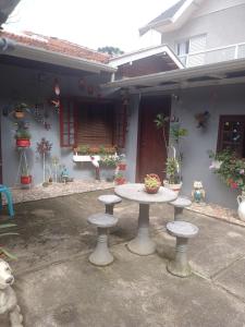a table in front of a house with potted plants at Aconchego da Wal in Campos do Jordão