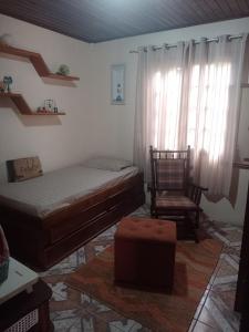 a bedroom with a bed and a chair at Aconchego da Wal in Campos do Jordão