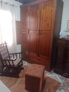 a living room with a wooden cabinet and a chair at Aconchego da Wal in Campos do Jordão +1 photo