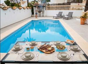 a table with plates of food next to a swimming pool at Vista Portet, sleeps 10, Private Pool, Sea Views, Squash, 1 km from El Portet beach in Teulada