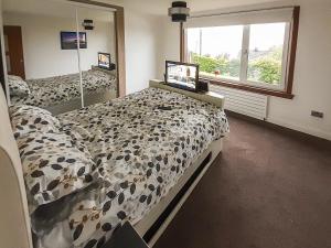 a bedroom with a bed with a comforter and a window at Hilbre in Strachur +7 photos