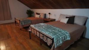 two beds in a room with wooden floors at Windwood Cabin Cerro Azul in Los Altos de Cerro Azul