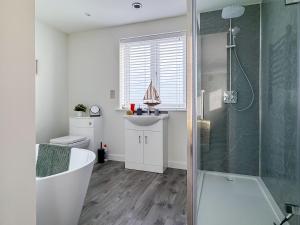 a bathroom with a tub and a shower and a sink at Seafields in Sidestrand