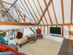 a living room with a tv and a couch and chairs at Liston Hall Barn in Gosfield
