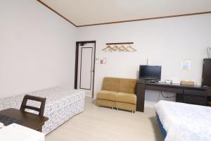 a room with two beds and a desk and a chair at ペンション星砂 in Zamami
