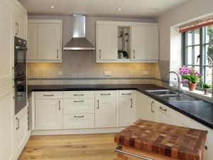 a kitchen with white cabinets and a sink at Kites Gate Cottage in Kingham