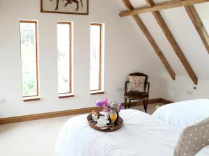 a bedroom with two beds and a table with flowers on it at Kites Gate Cottage in Kingham