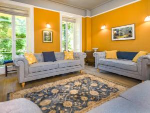 a living room with two couches and an orange wall at Plas Bodegroes in Pwllheli