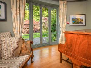 a living room with a piano and a couch at Plas Bodegroes in Pwllheli +55 photos