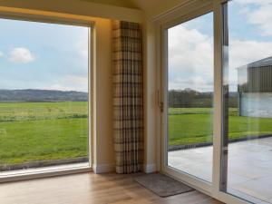 an open glass door with a view of a field at Falcon Cottage in Linlithgow