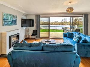 a living room with blue couches and a fireplace at River View-Ukc6112 in Brundall