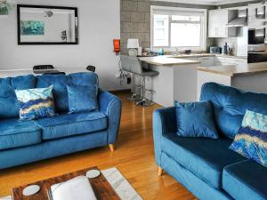a living room with two blue couches and a kitchen at River View-Ukc6112 in Brundall