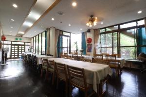 a dining room with tables and chairs and windows at ペンション星砂 in Zamami