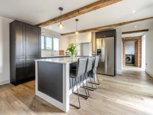 a kitchen with a large island with bar chairs at The Dairy - Uk44130 in Baystonhill
