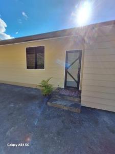 a yellow house with a door on the side of it at Temoe'ani House in Uturoa +4 photos