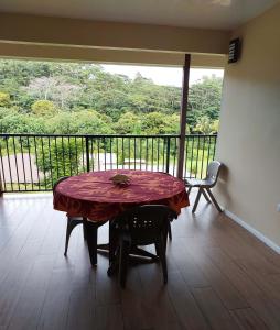 a table and chair in a room with a balcony at Temoe'ani House in Uturoa