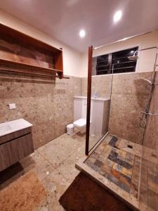 a bathroom with a shower and a toilet and a sink at Temoe'ani House in Uturoa