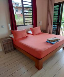 a bedroom with a bed with red sheets and a window at Temoe'ani House in Uturoa