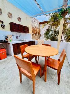 a wooden table and two chairs and a table and a kitchen at Costa Rentals Palmar & Wasi in Brisas de Zicatela