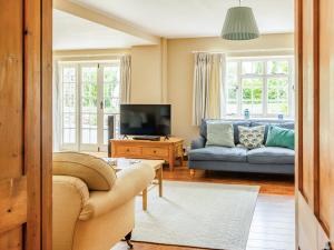 a living room with a couch and a tv at Lower Barrowfield Farm in Beaminster