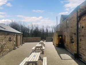 a row of wooden benches sitting in a courtyard at Wagtail Cottage-Ukc6984 in Castleside