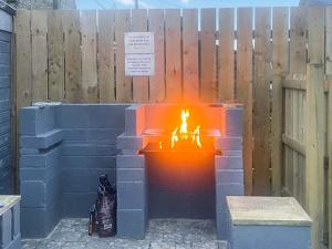 a fire pit made out of bricks in front of a fence at Wagtail Cottage-Ukc6984 in Castleside
