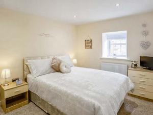 a bedroom with a large white bed and a television at Wagtail Cottage-Ukc6984 in Castleside