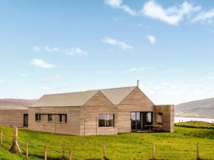 a wooden house on a hill with a green field at The Two Byres in Trumpan