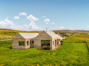 a house on a hill with a green yard at The Two Byres in Trumpan