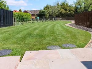 a garden with a lawn and a fence at Holly Barn in Ashwellthorpe