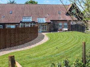 a house with a fence and a yard at Holly Barn in Ashwellthorpe