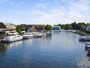 a group of boats docked in a river with houses at Holly Barn in Ashwellthorpe