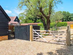 a wooden gate with a fence in front of a tree at Holly Barn in Ashwellthorpe
