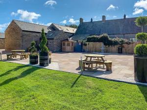 a patio with two picnic tables in front of a building at Barn Owl Cottage- Ukc6985 in Castleside