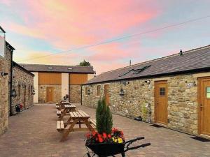 a patio with wooden benches and tables with a sunset at Barn Owl Cottage- Ukc6985 in Castleside