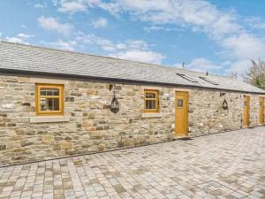 a stone house with yellow doors and a brick driveway at Peewit Cottage-Ukc6986 in Castleside